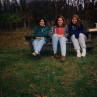 three students sitting on bench